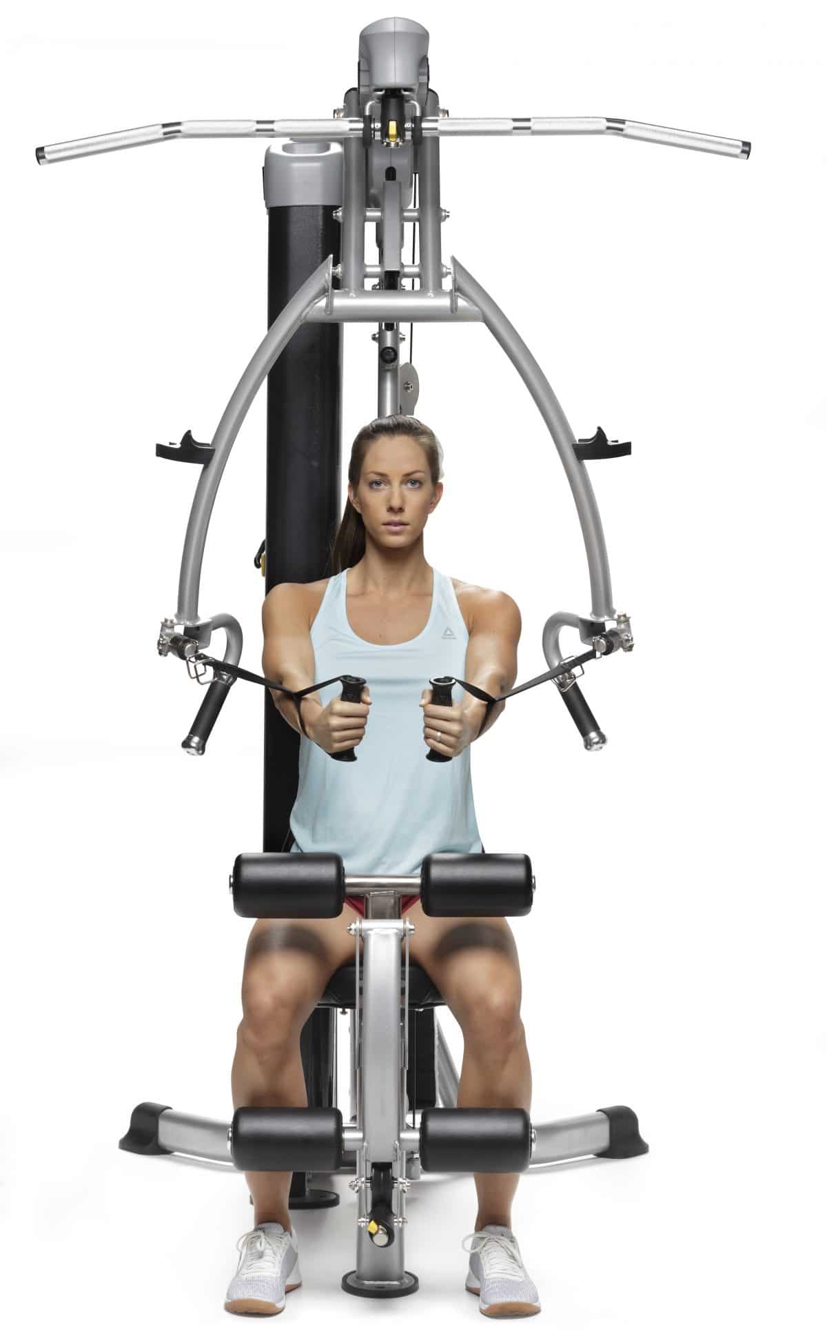 A woman is sitting on a gym machine.