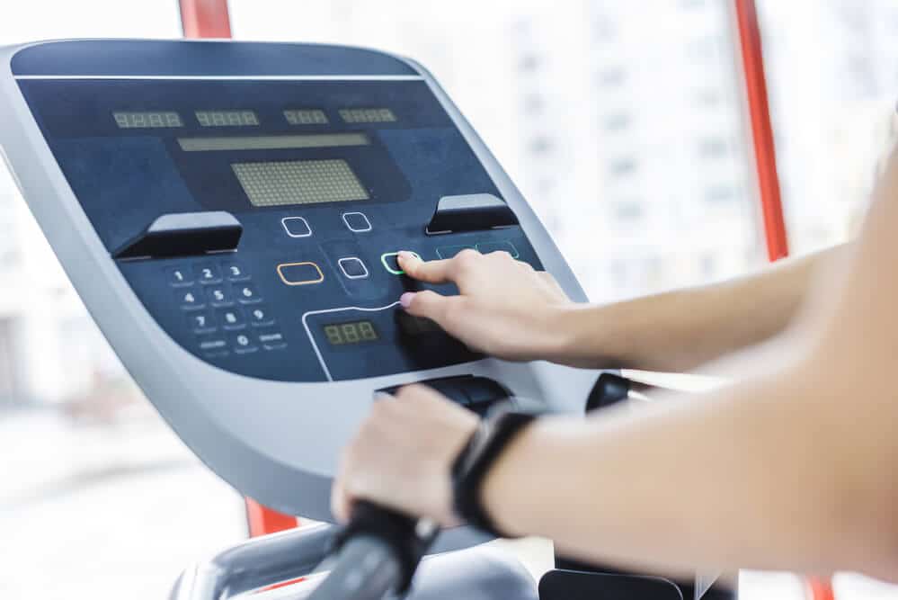 woman changing the settings of elliptical machine